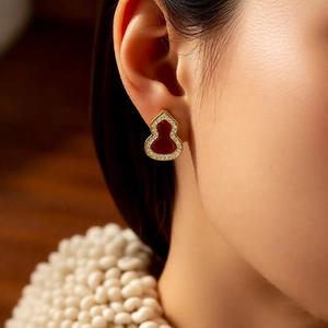 Detailed close-up of red hulu gourd stud earring with gold plating and cubic zirconia
