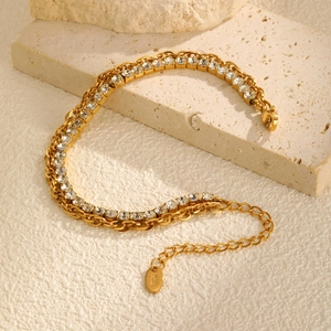 Detail shot of golden double chain bracelet with green zircon on textured stone base