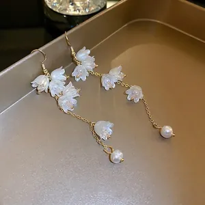 Boucles d'oreilles muguet élégantes avec fleurs en résine et perles sur plateau