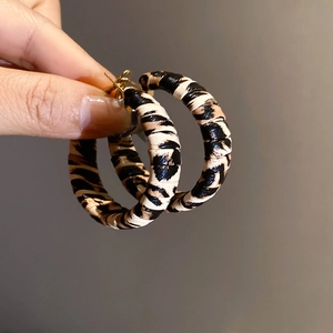 Close-up of C-shaped acrylic hoop earrings with a classic leopard print texture