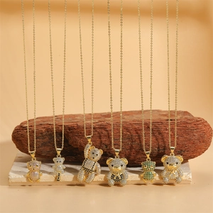 Gold necklaces featuring colorful zircon teddy bear pendants on natural stone display