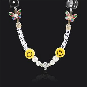 Close-up of mixed beaded necklace with pearls, skull pendant, dice, and smile charms