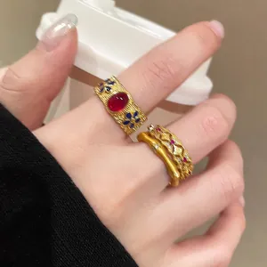 Macro detail of retro gold enamel bamboo ring with red oval gemstone and blue floral accents