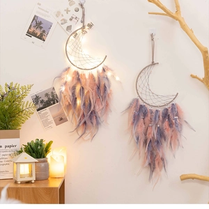 Detail of moon-shaped dreamcatcher with pink feathers, white pearls and warm LED lights
