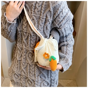 Close-up of handmade crochet bucket bag with carrot decor and woven flower detail