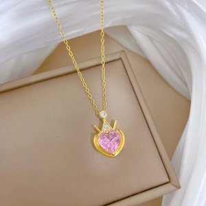 Detailed shot of pink heart gemstone necklace with gold crown and crystals on jewelry box