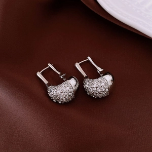 Macro detail of silver U-shaped zircon earrings with sparkling pave-set stones on satin