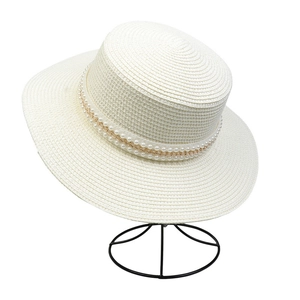 Close-up of wide brim straw hat featuring elegant pearl and gold chain decoration