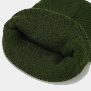 Gros plan détaillé du bonnet en maille côtelée vert foncé montrant la texture de laine