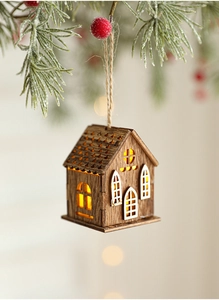 Dettaglio di una casetta di Natale in legno con luce LED calda appesa all'albero festivo