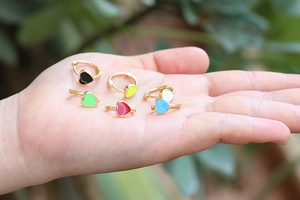 Colorful enamel heart hoop earrings in six vibrant colors held on palm with natural light