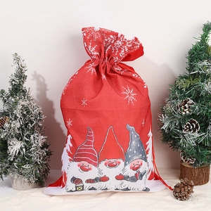 Close-up of red linen Christmas gift bags with gnome illustrations and snowflake prints
