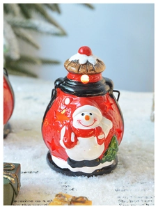 Détail d'une lanterne bonhomme de neige en céramique rouge avec lumière LED festive