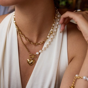 Detail of 18K gold chain and freshwater pearl necklace with a textured heart pendant