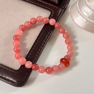 Detailed view of pink natural stone beads bracelet with a single orange agate bead