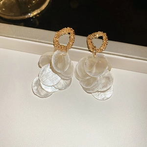 Detailed view of golden round hoop earrings with layered white shell pendants