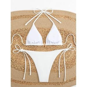 White halter bikini set with gold starfish charm on round straw mat, beach vacation style