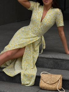 Detail of yellow floral wrap dress featuring V-neckline and tie waist on model