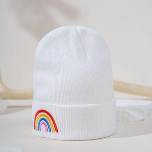 Detail of white knit beanie showing colorful rainbow embroidery and warm texture