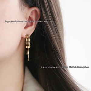 Detail view of 18K gold plated tassel earrings with multi-row beaded chains on earlobe