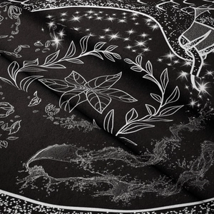 Close-up of bohemian tapestry fabric showing white star and floral patterns on black background