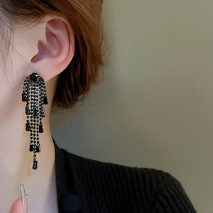 Gros plan de longues boucles d'oreilles à pompons noirs et strass sur le mannequin