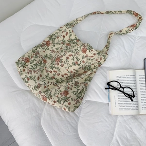 Detailed macro view of floral canvas tote bag on bedding with lifestyle props