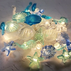 Macro shot of seashell and starfish LED string lights with warm glowing resin ornaments