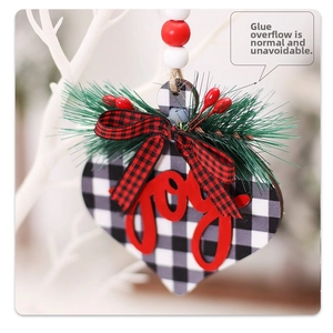 Detail of wooden heart ornament with buffalo plaid and red 3D Joy lettering on tree