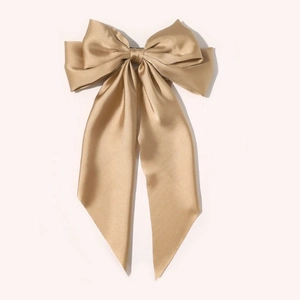 Detail of elegant champagne gold satin oversized bow hair clip with flowing ribbons
