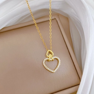 Detail of gold double heart pendant necklace with rhinestones on white silk