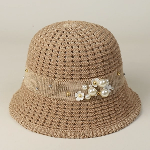 Close-up of elegant woven straw hat with pearl accents and 3D flower decorations