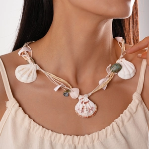 Detail shot of a handmade raffia woven shell necklace on a model for a beach holiday vibe