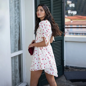 Détail d'une robe d'été blanche avec motif cerises dans un décor de balcon italien