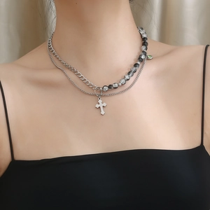 Detail of layered titanium steel necklace with cross pendant and beaded chain for men