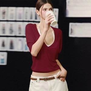 Detail of burgundy long-sleeve knit top with V-neckline on a female model