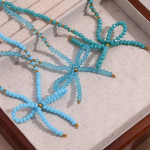 Macro detail of blue faceted crystal beads and gold beads with a bow pendant on a tray