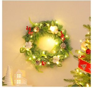 Detail of Christmas wreath with pine cones, red berries, cotton and warm LED lights