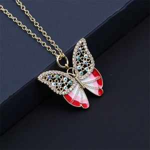 Close-up of butterfly pendant with red enamel and pavé stones on gold-plated chain