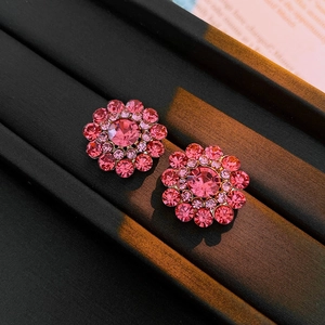 Detail of pink crystal flower stud earrings with shimmering rhinestones on black stand