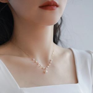 Elegant freshwater pearl necklace with gold chain in V-shape design worn by a model