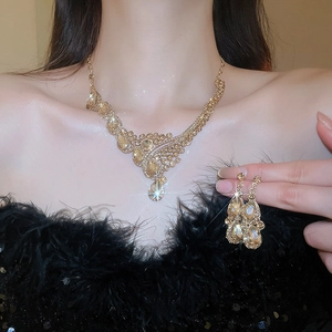 Close-up of luxury water drop pendant necklace and earring set with golden crystals