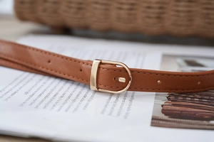 Macro shot of brown leather strap with golden D-ring buckle and fine stitching detail