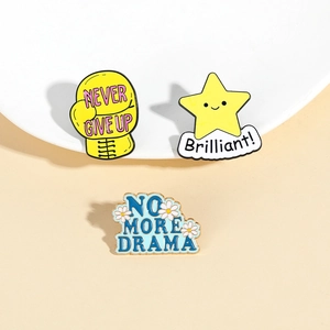 Close-up of alloy enamel pins featuring Never Give Up and No More Drama lettering