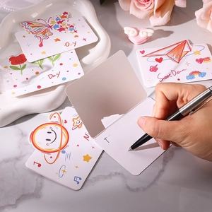 Une main écrivant un message sincère sur une jolie carte de vœux illustrée de dessins animés.