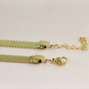 Macro detail of golden metal mesh choker necklace with lobster clasp and extender chain