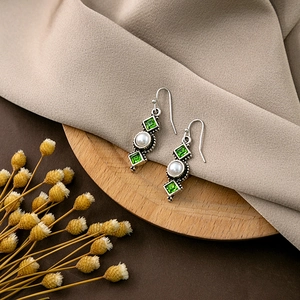 Detailed view of bohemian vintage earrings with green crystals and pearls on wood