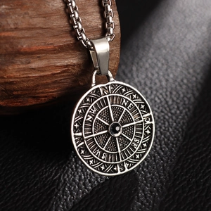 Macro shot of silver compass pendant necklace with black gemstone on vintage wood