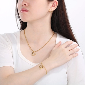 Vue détaillée d'une parure de bijoux cœur doré portée par un mannequin femme