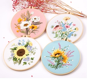 Detailed view of four round DIY floral embroidery hoops with sunflower and daisy patterns